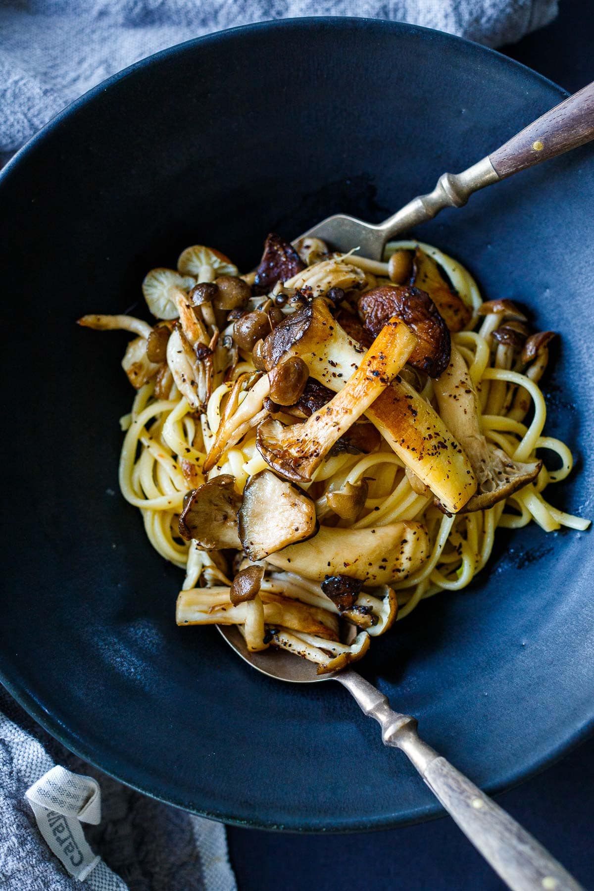 miso pasta recipe in a black serving bowl topped with mushrooms.