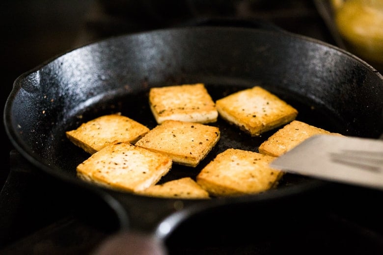 cooking crispy tofu in a cast iron skillet.