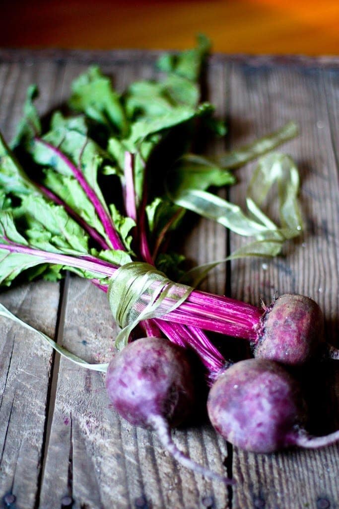 bunch of purple beets on a wood table. 
