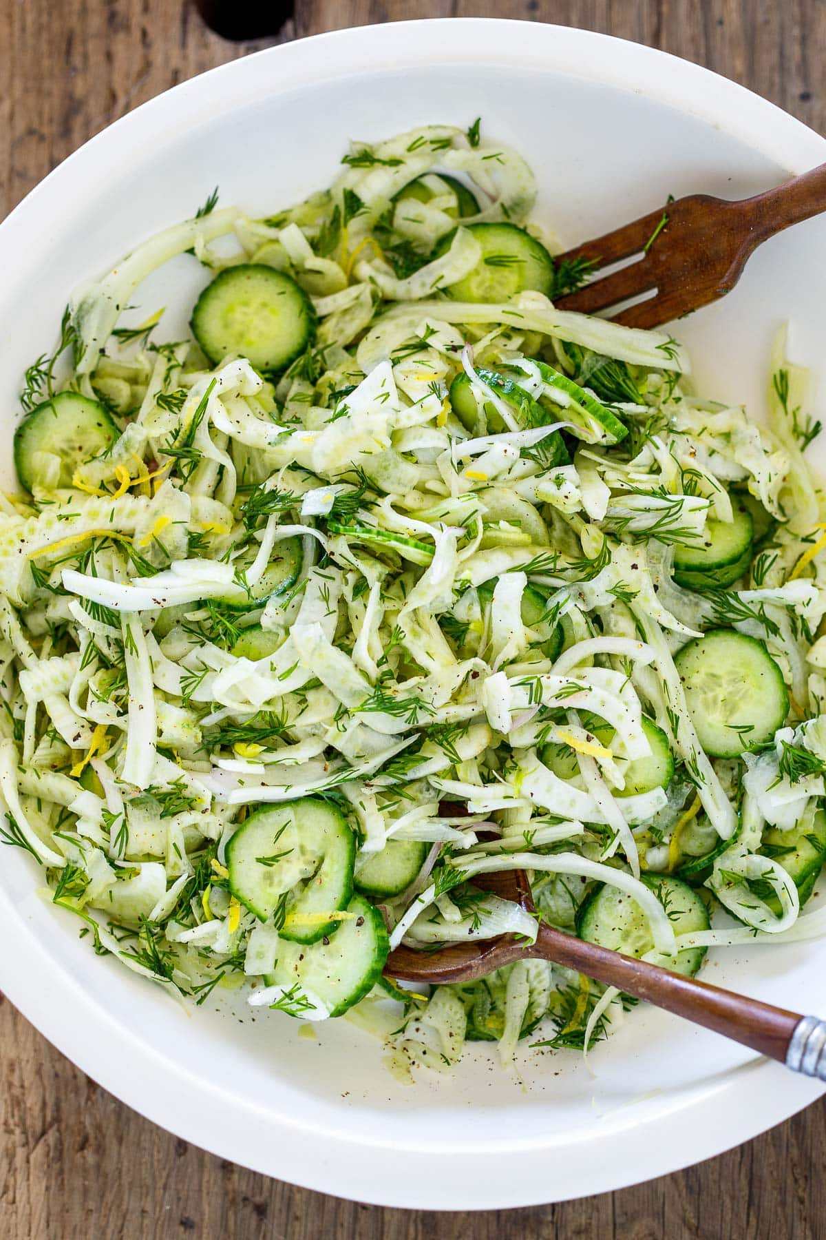 Tossing the fennel salad with the lemon juice , olive oil, dill, salt and pepper. 