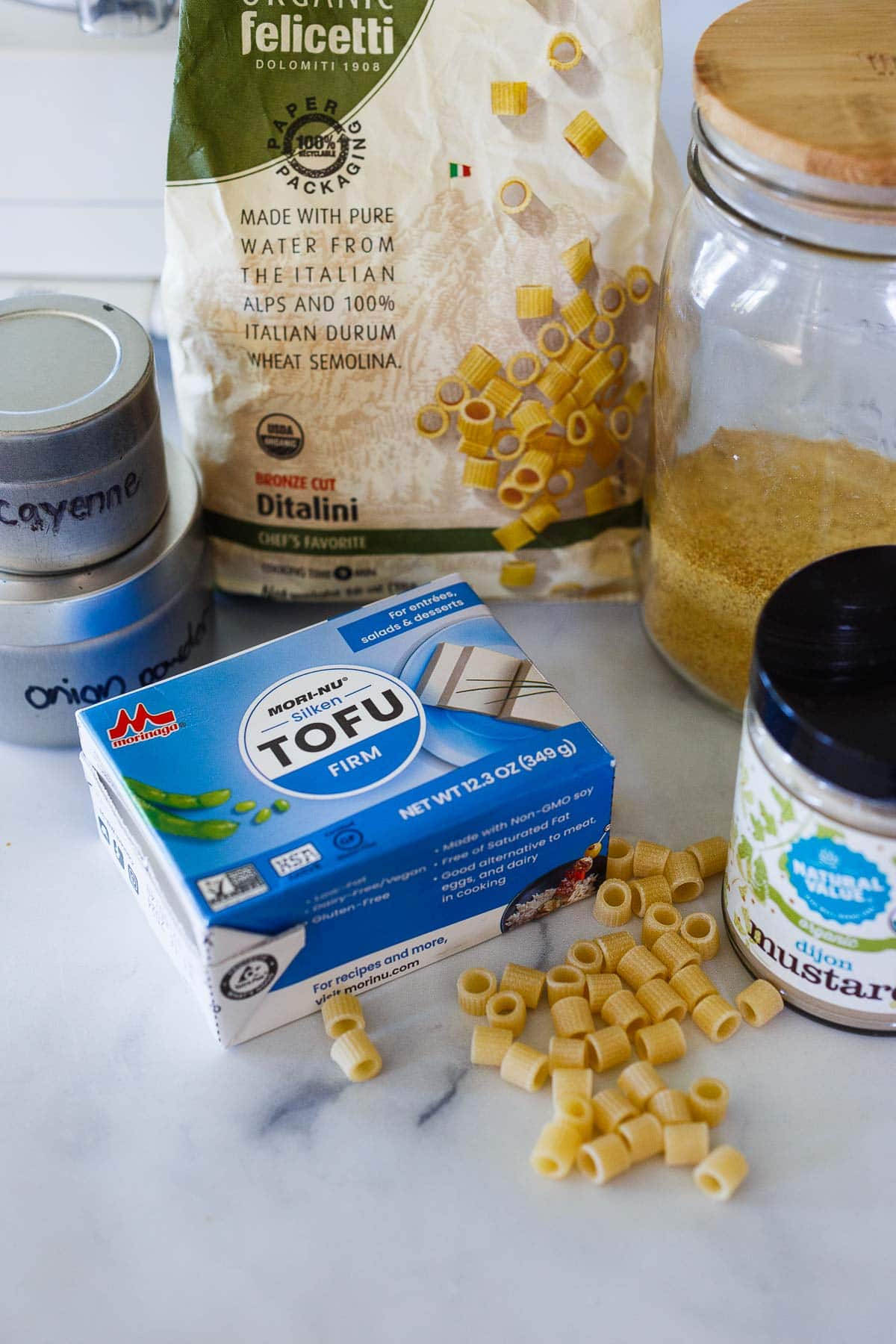 ingredients laid out for vegan mac and cheese - ditalini pasta, nutritional yeast, dijon mustard, silken tofu, cayenne, onion powder.