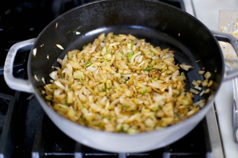 Onions and fennel sautéing in a pan.