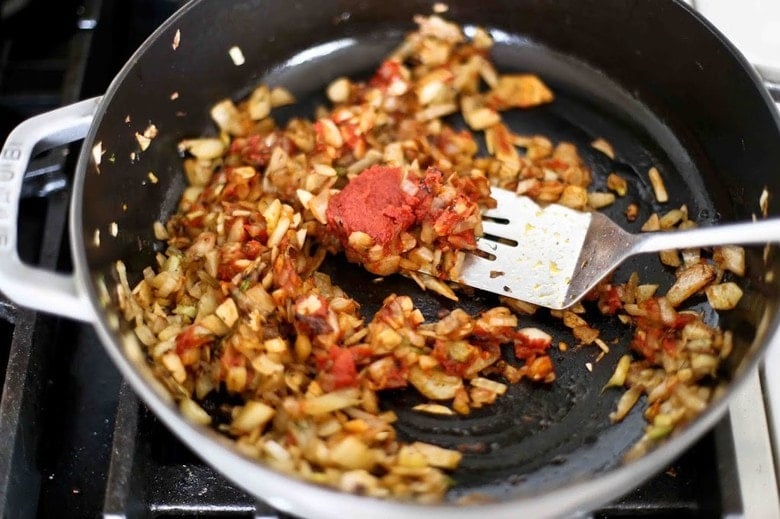 Frying savory paste for the stew in a pot on the stove.