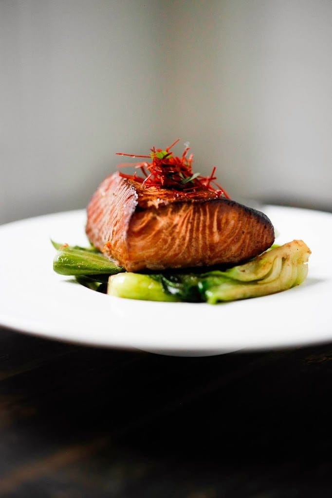 tea smoked salmon over bok choy on a white plate.