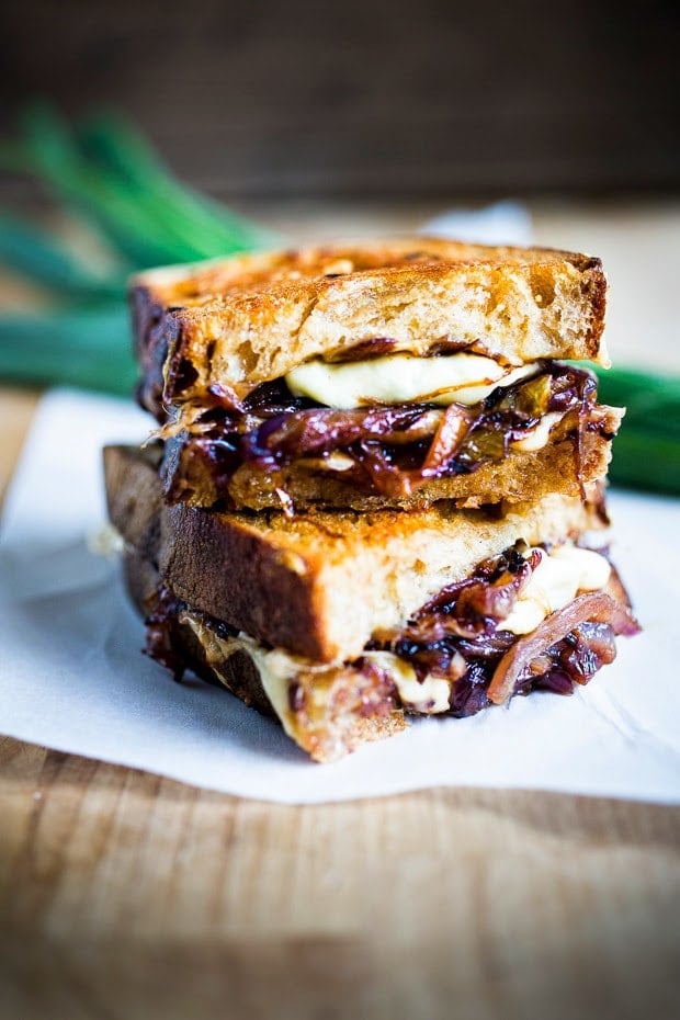 French onion grilled cheese halves stacked on parchment. 