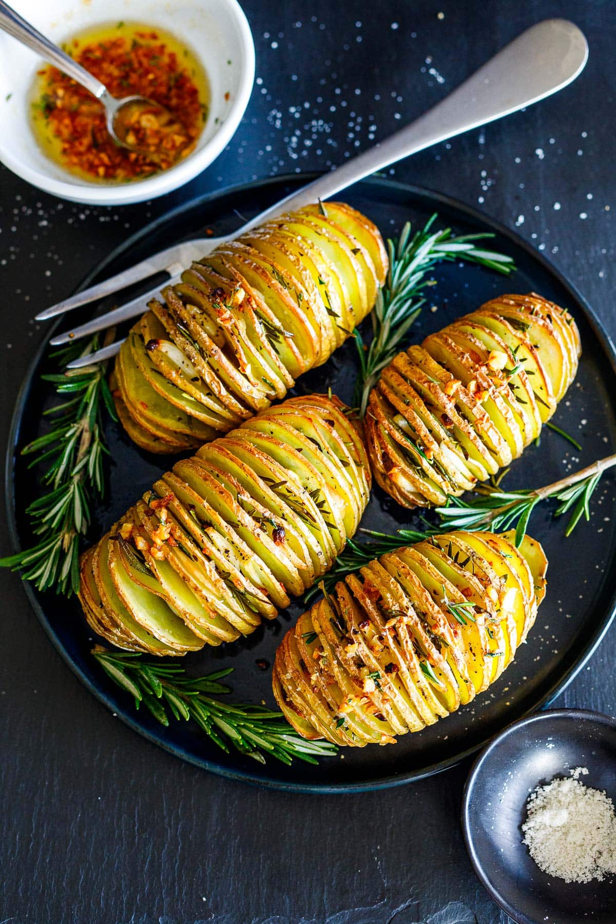 Golden brown Hasselback Potatoes on a serving platter.