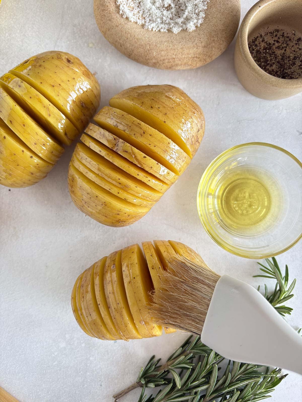 Brushing hasselback potatoes with olive oil.
