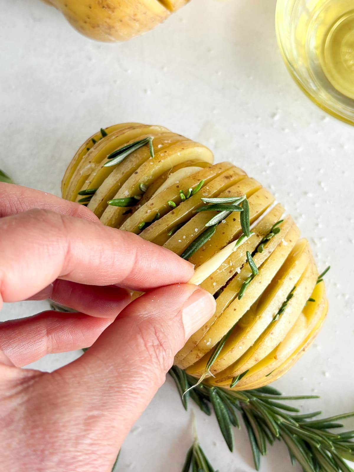 Stuffing Hasselback Potatoes with rosemary and garlic.