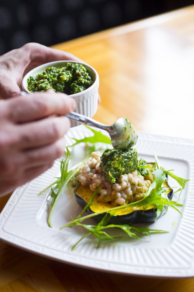 spooning  pesto on top of farro risotto.
