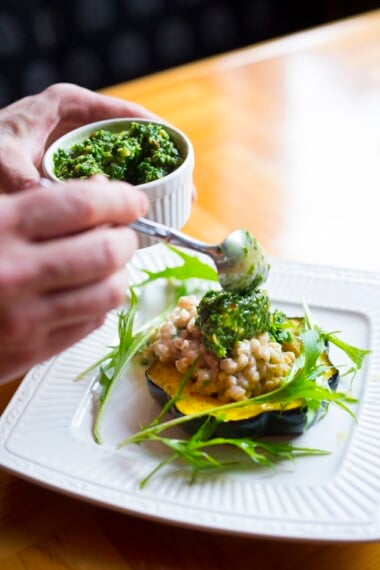 This Farro Risotto is cozy and delicious! Served with roasted acorn squash, and a flavorful pesto, this vegetarian dinner recipe is perfect for fall!