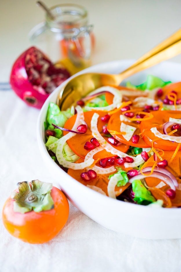 Persimmon, pomegranate and shaved fennel salad with honey citrus dressing. vegan, gf | www.feastingathome.com salad bowl with persimmon salad with fennel and pomegranate served with a gold serving spoon.