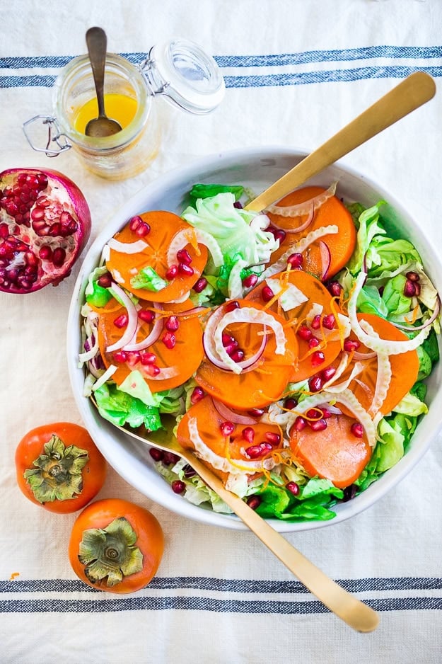 Persimmon, pomegranate and shaved fennel salad with honey citrus dressing. vegan, gf | www.feastingathome.com large serving bowl with persimmon salad with butter lettuce, fennel, and pomegranate seeds, with gold serving utensils.