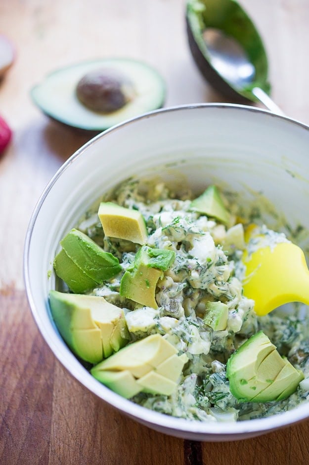 egg salad in bowl with diced avocado on top.