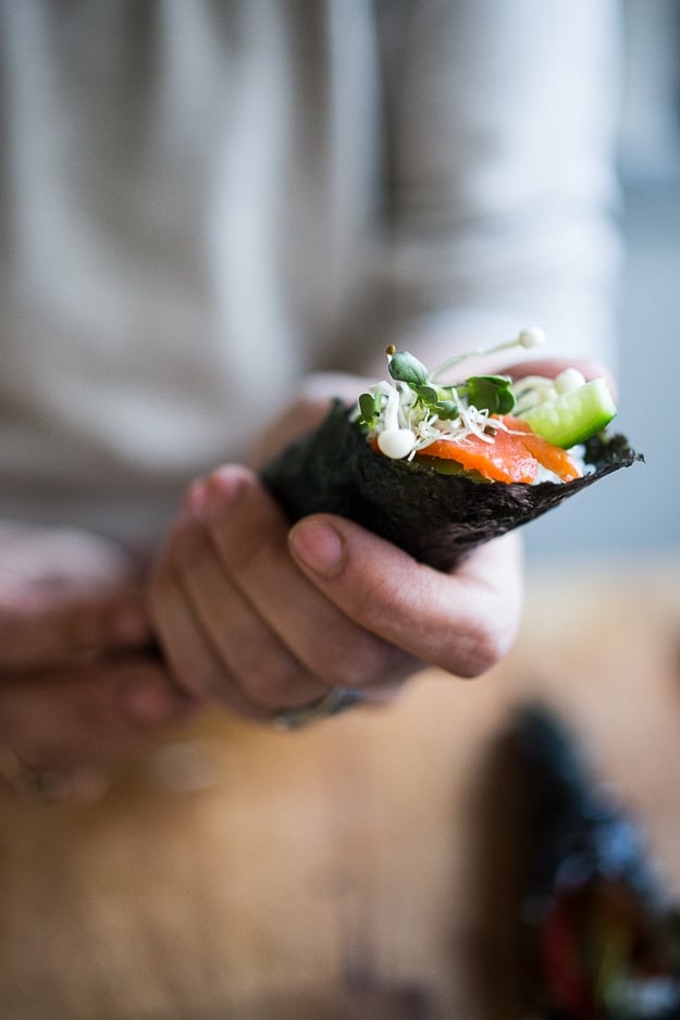 a temaki hand roll in hands. 