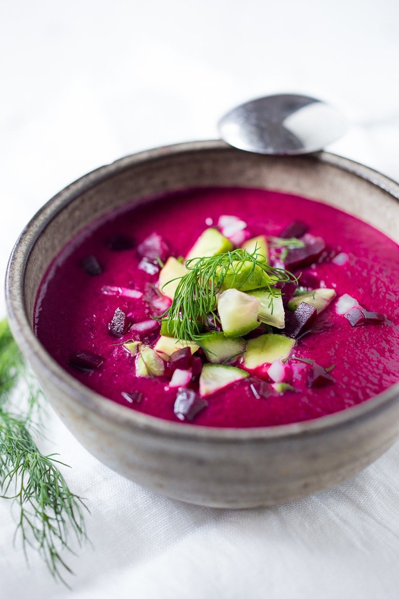 simple beet gazpacho in soup bowl with diced beet, cucumber, avocado, and dill as garnish.