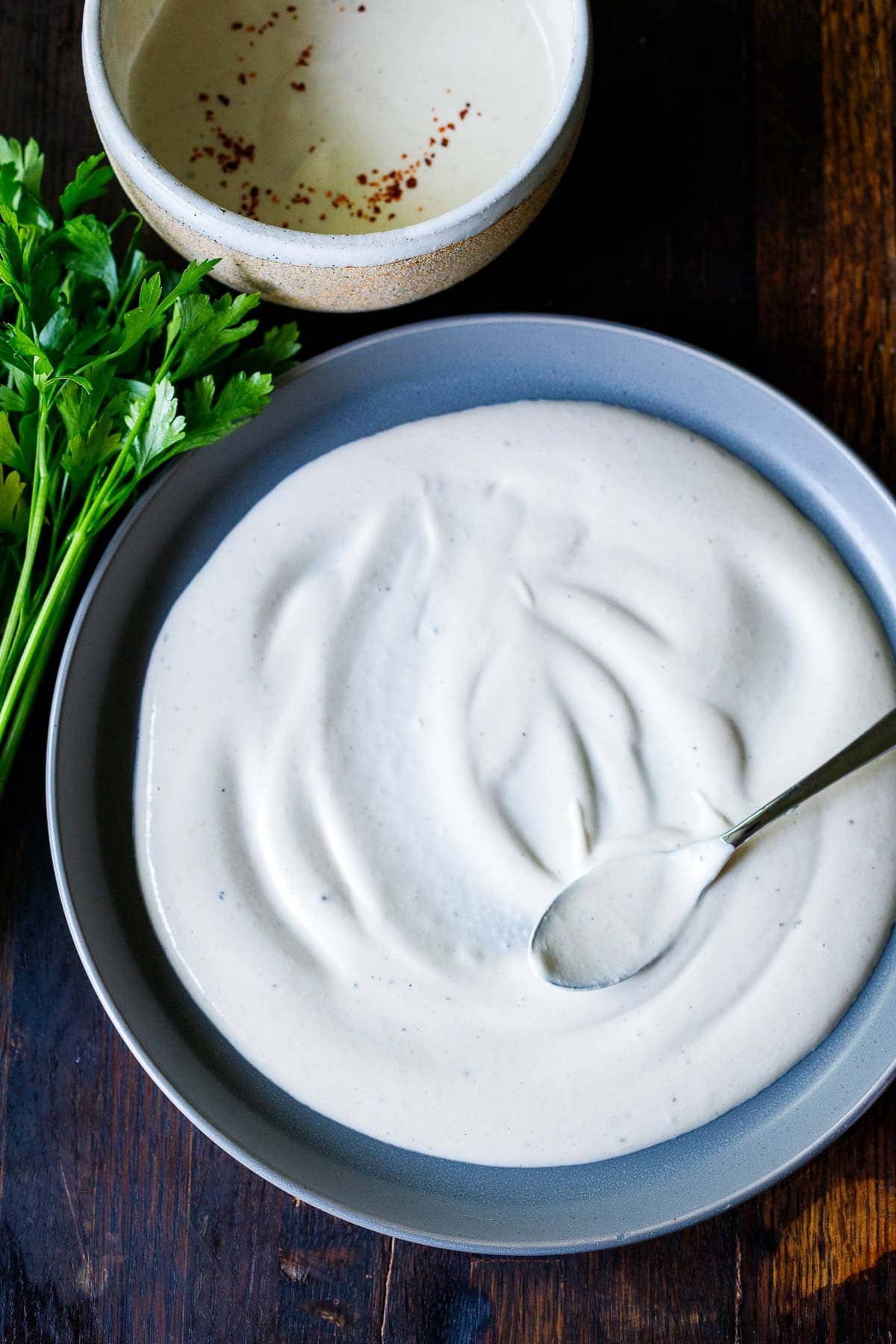 spreading tahini yogurt on a plate.