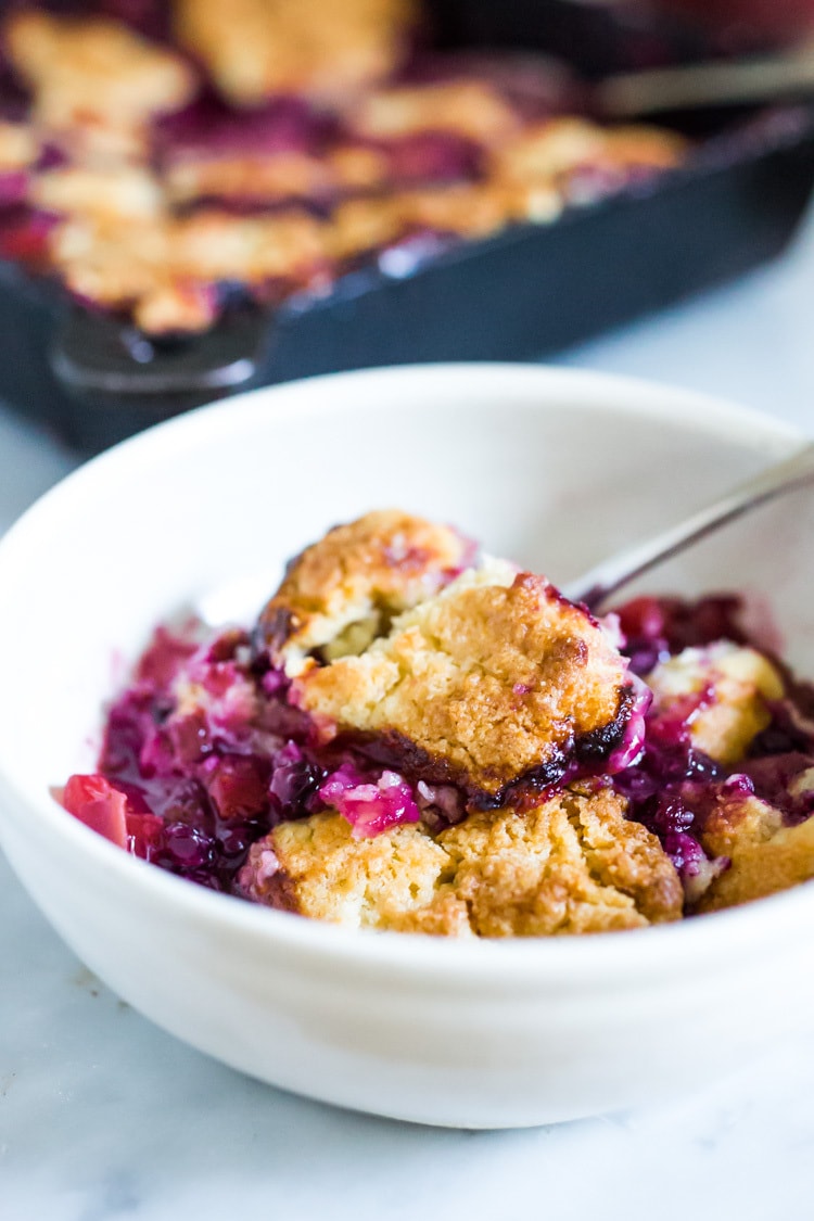 This Peach Skillet Cobbler is topped with a golden and delicious, biscuit topping with fresh summer peaches and berries. This can be made gluten-free and or vegan! #peachcobbler #skilletcobbler #summer #desserts #peachdesserts #huckleberries #vegancobler #glutenfreecobbler #vegandessert 