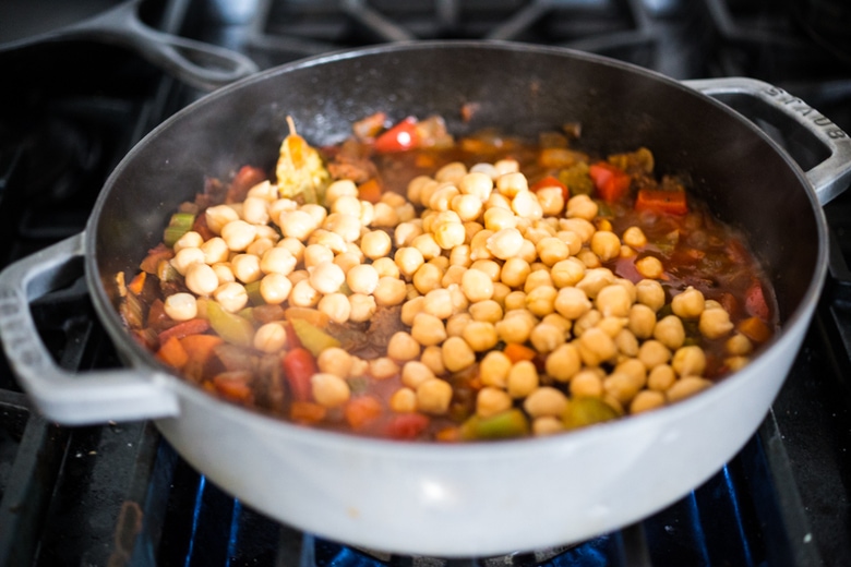adding the chorizo and chickpeas to the stew.
