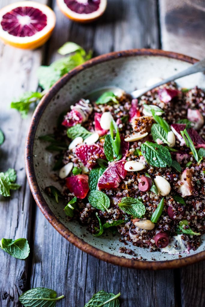 Moroccan quinoa salad with mint and oranges and almonds in speckled bowl. 