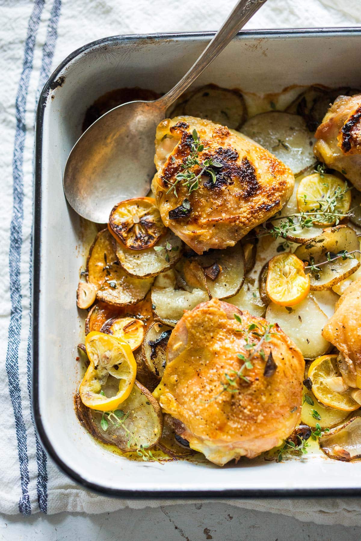 Oven-baked chicken thighs, roasted over thinly sliced potatoes with garlic, lemon and thyme. 