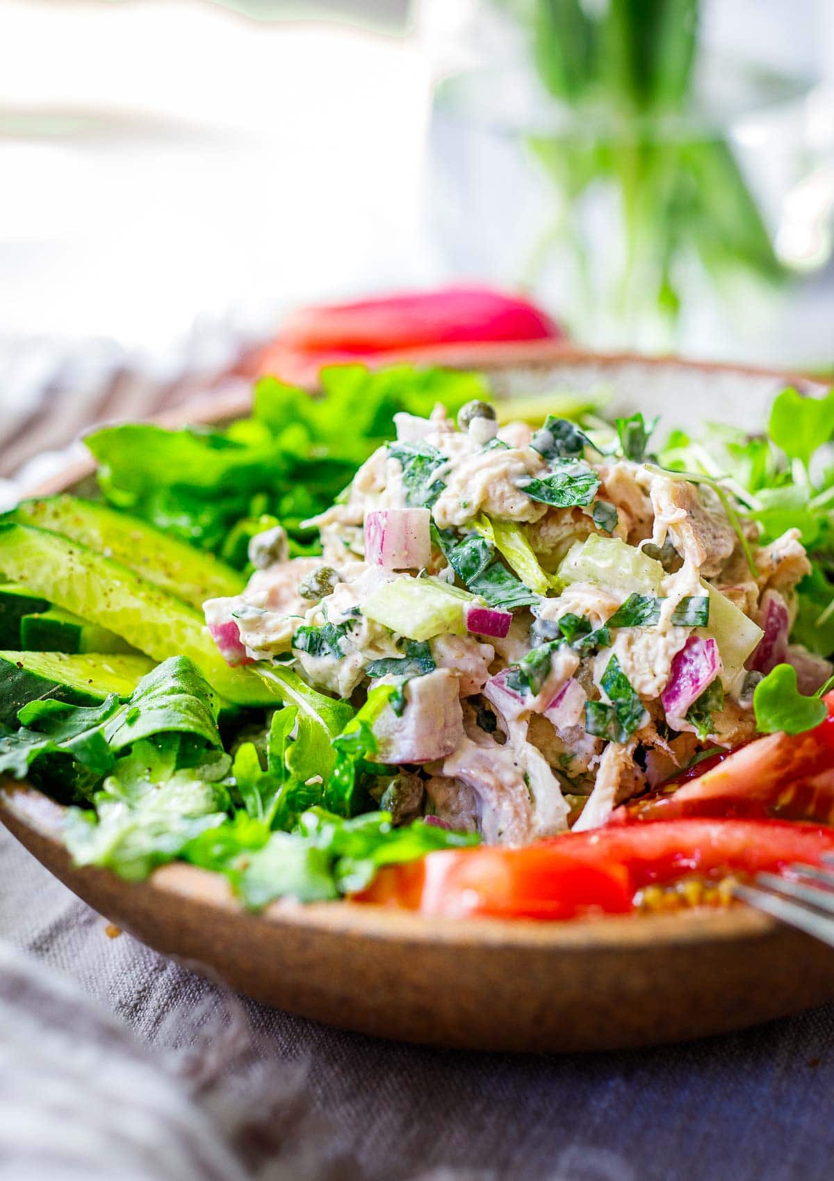 chicken salad recipe served over greens with tomatoes and cucumber
