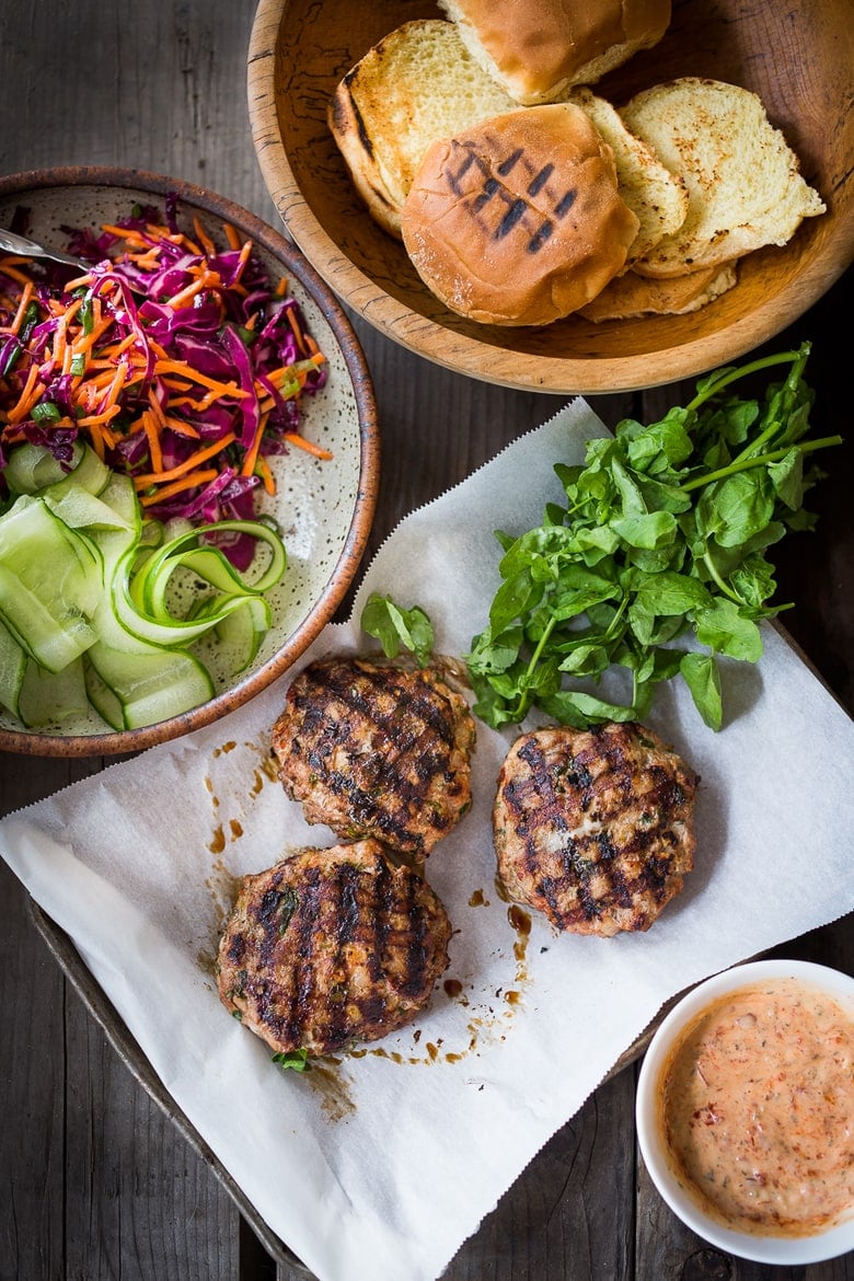 Assembling the turkey burgers with buns, slaw, sriacha aioli and grilled burger patties. 