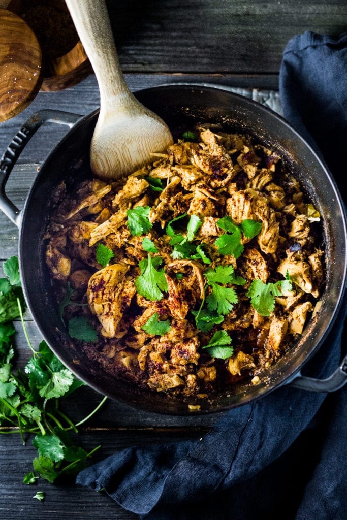 cast iron pan with chicken carnitas garnished with fresh cilantro.