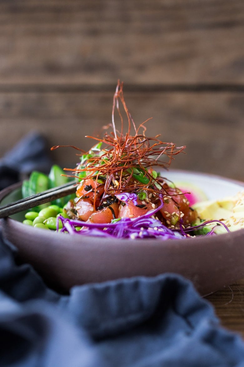 poke bowl with ahi tuna served with sliced cabbage, edamame, sesame seeds, and chili threads.