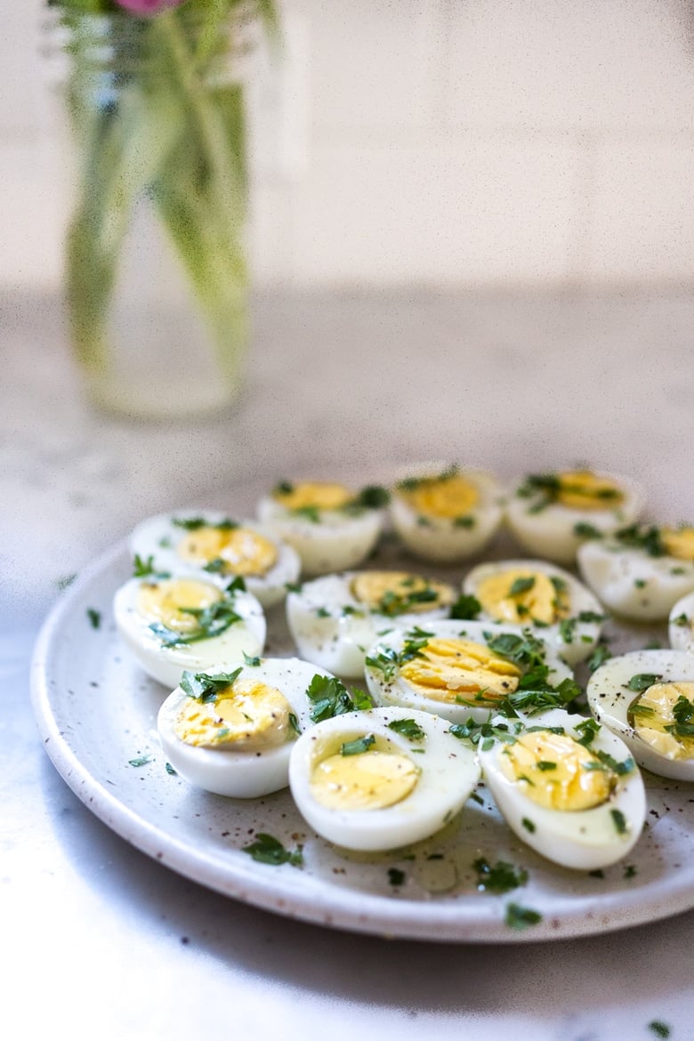 Quick and Easy Hard boiled eggs with olive oil, fresh herbs and pickled shallots, a simple, make ahead brunch recipe that is  perfect for gatherings and potlucks. Think of these like deviled eggs but in ½ the time! #deviledeggs #hardboiledeggs #boiledeggs #brunchrecipe 