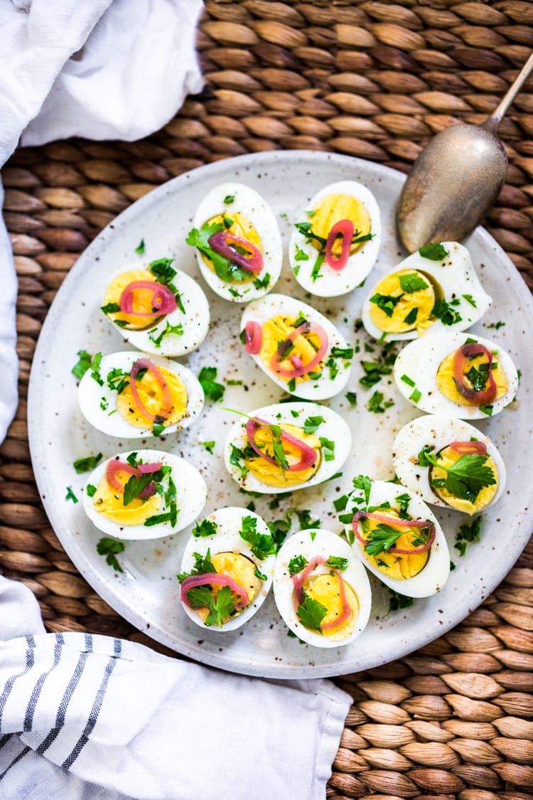 Quick and Easy Hard boiled eggs with olive oil, fresh herbs and pickled shallots, a simple, make ahead brunch recipe that is  perfect for gatherings and potlucks. Think of these like deviled eggs but in ½ the time! #deviledeggs #hardboiledeggs #boiledeggs #brunchrecipe 