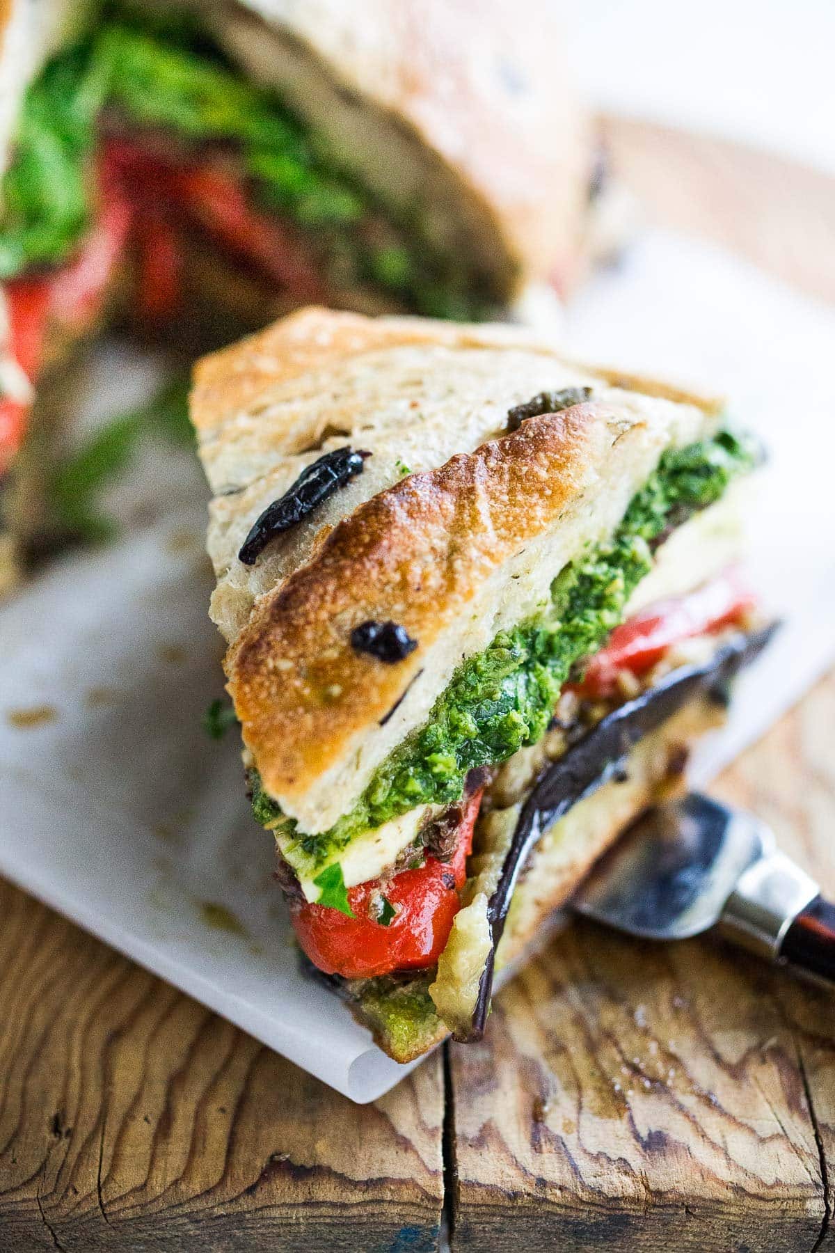 A beautiful slice of muffuletta sandhich on a cutting board. 