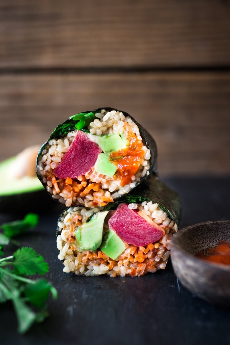 A Sushi burrito with ahi tuna, avocado, kimchi, cut in half and stacked. 