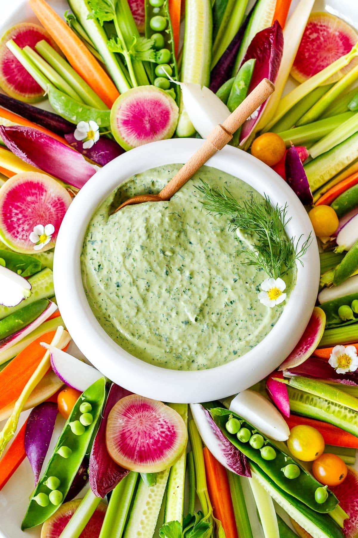 Green goddess dressing ( or dip) in a bowl with vegetable crudites. 