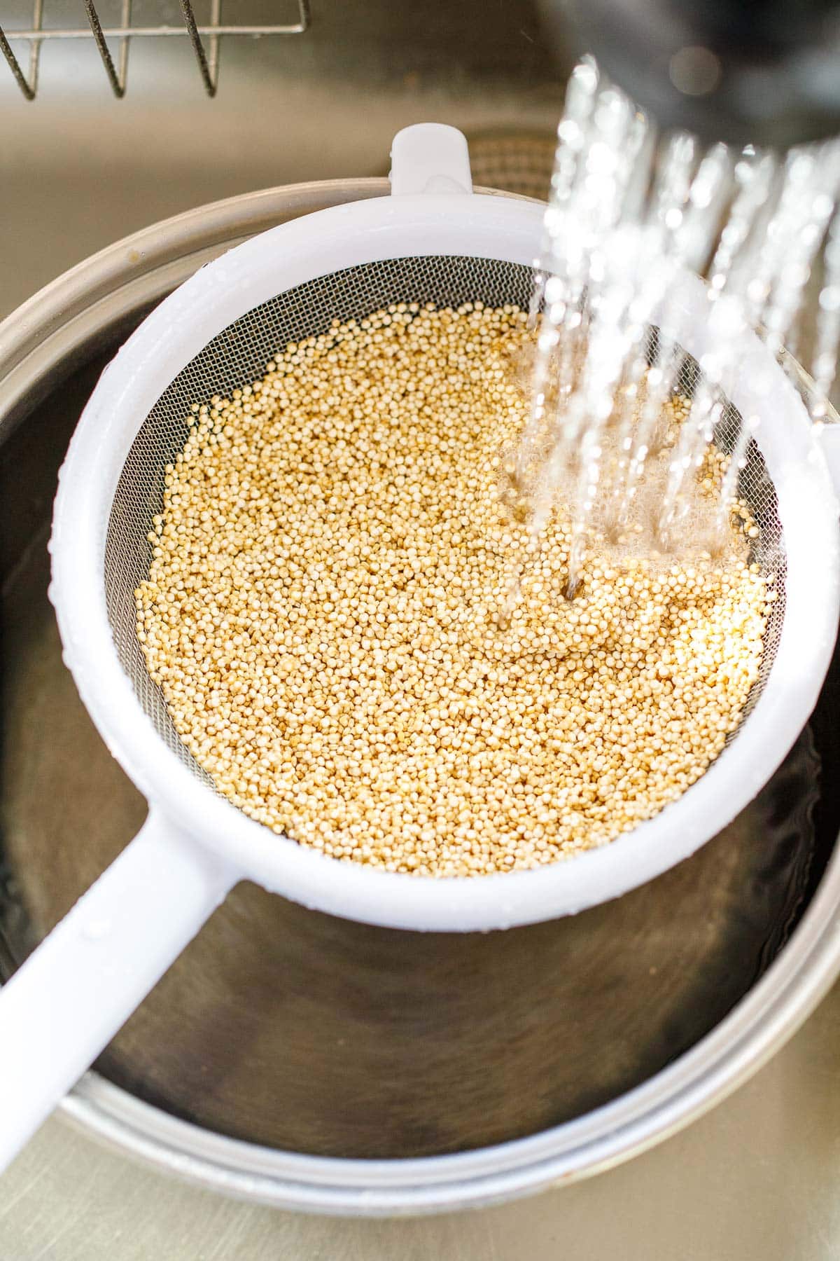rinsing quinoa in a strainer- this helps remove the bitterness.