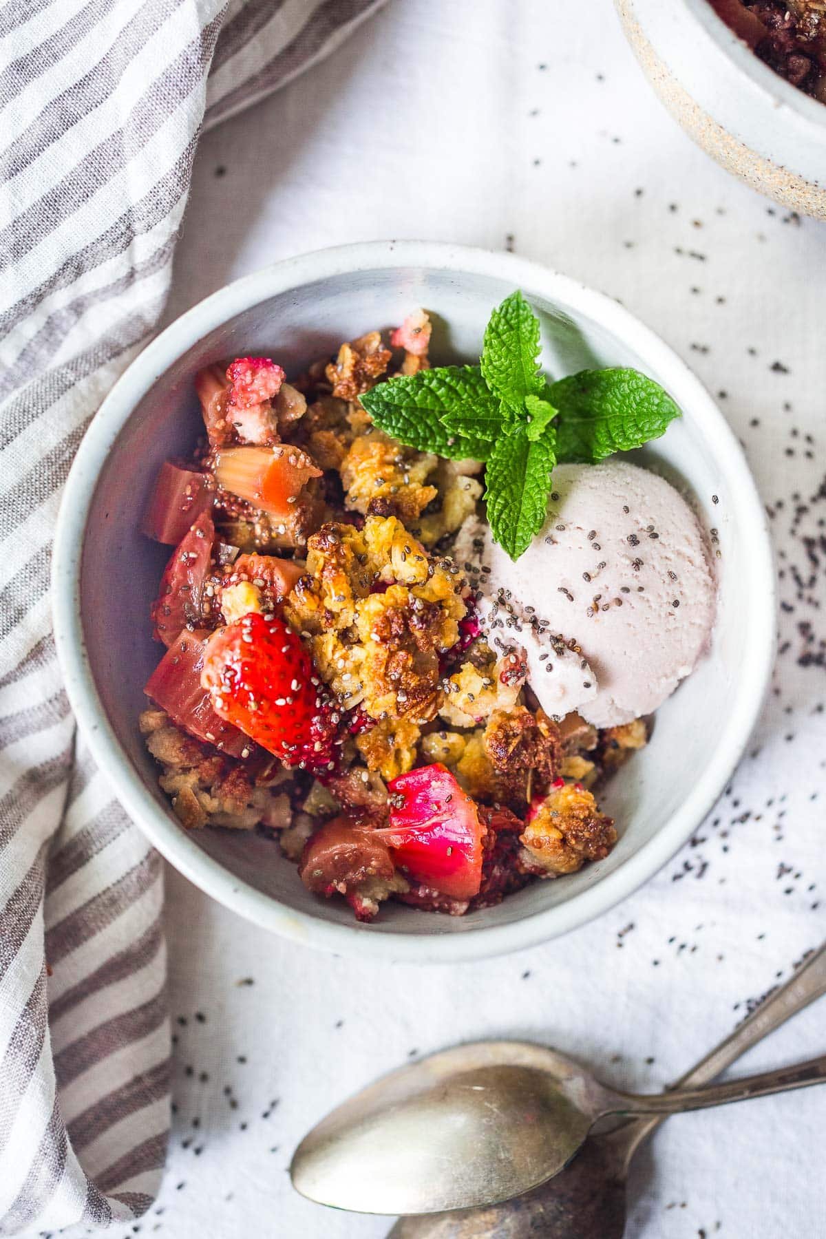 rhubarb crisp in a bowl with icecream and strawberries. 