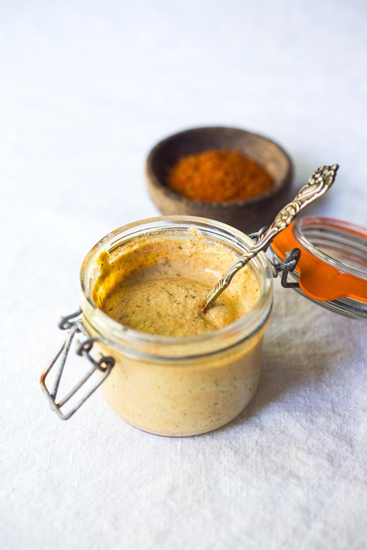 vegan cajun ranch dressing in small jar with spoon next to bowl with cajun spices.