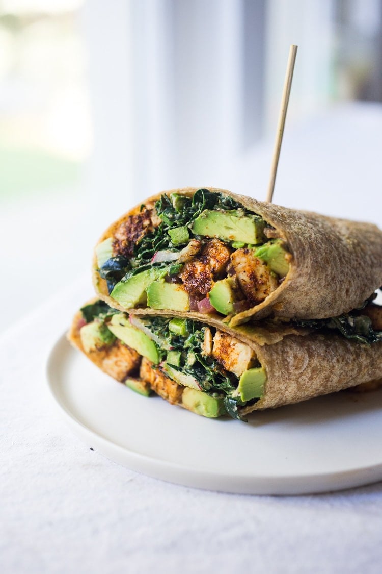 wheat wraps stacked with toothpick, made with cajun spiced blackened tempeh, avocado, and kale in creamy cajun ranch dressing.