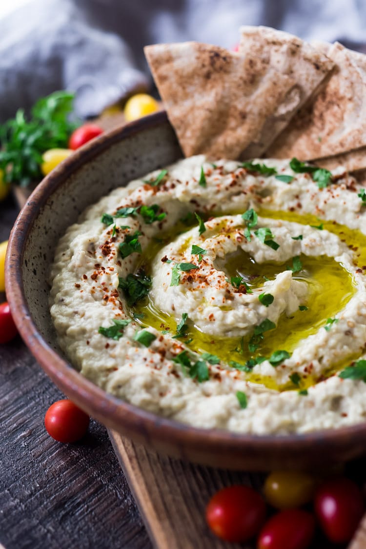 Baba Ganoush served n a bowl with a drizzle of olive oil, herbs and pita bread.