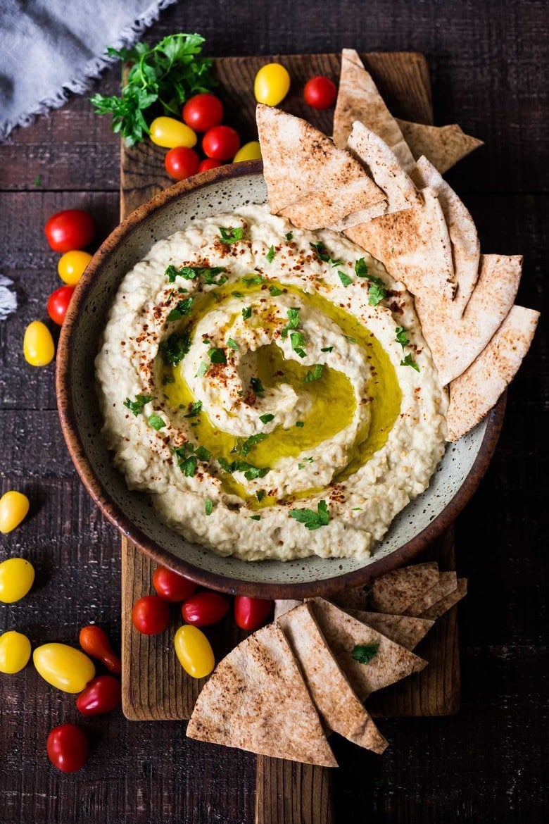 Baba Ganoush served n a bowl with a drizzle of olive oil, herbs and pita bread.