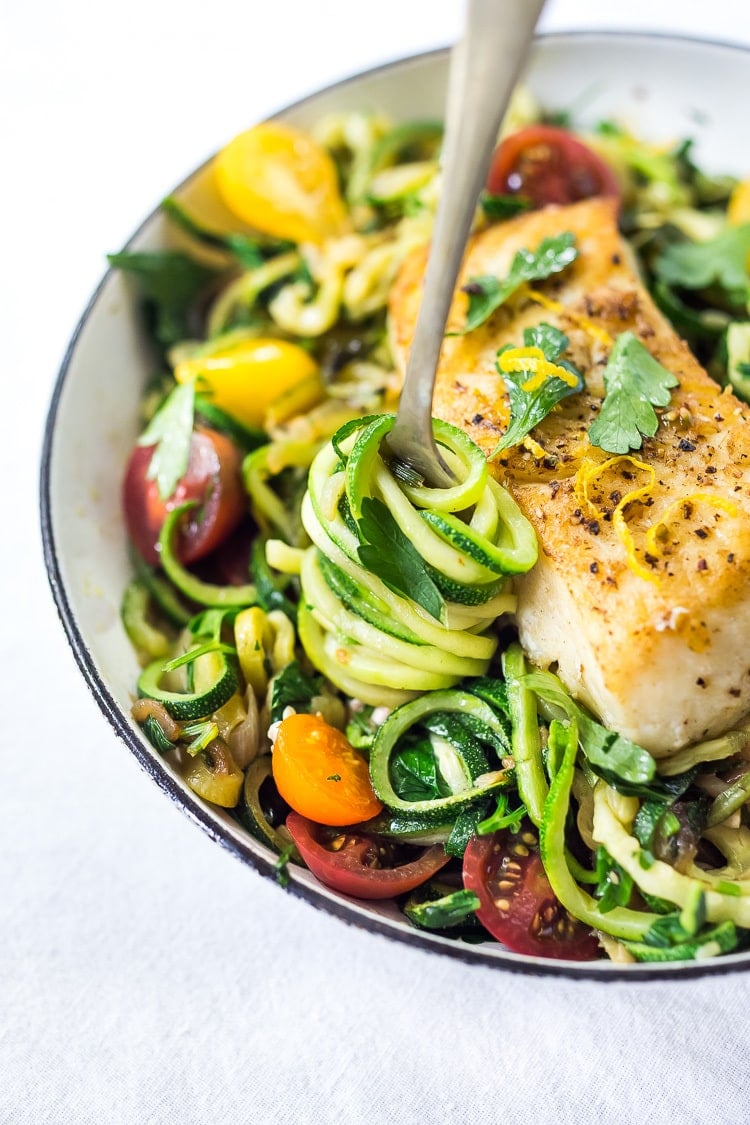 A simple, healthy Halibut recipe served over Lemony Zucchini Noodles with olive oil, garlic and parsley, topped with sweet summer tomatoes. A quick and easy low-carb meal! #keto #zucchininoodles #zoodles #halibut #halibutrecipes #lowcarb #healthy 
