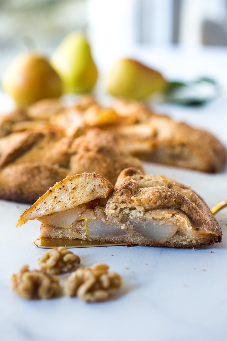slice of pear galette on gold serving spatula - side view of caramelized, juicy pears. 