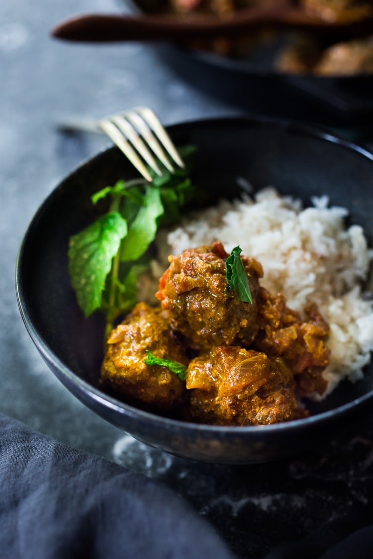 bowl with rice, mint, and lamb meatballs in Indian curry sauce.