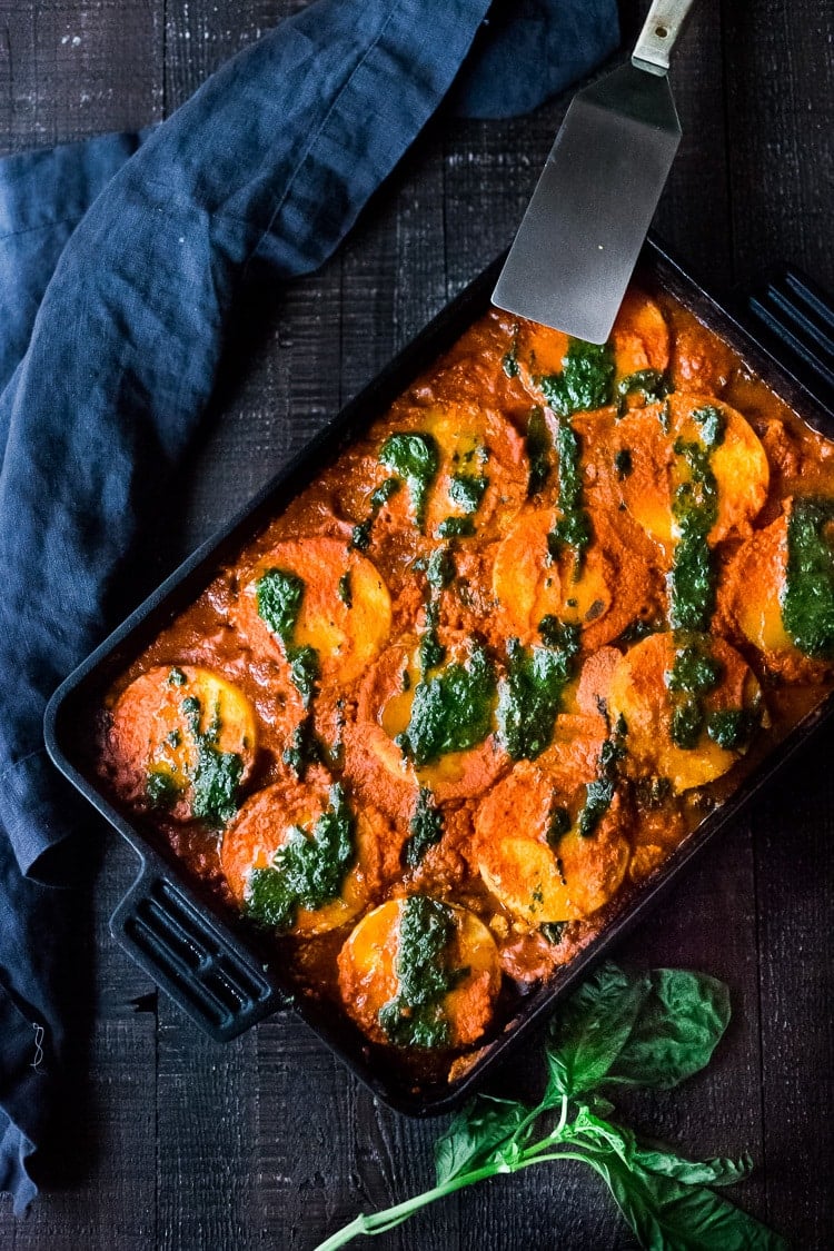 A pan of baked polenta lasagna with pesto drizzle.