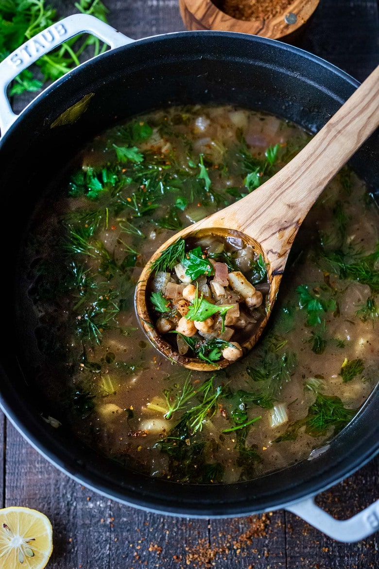 large pot of lemony chickpea soup with wood ladle scooping up a spoonful of soup. 