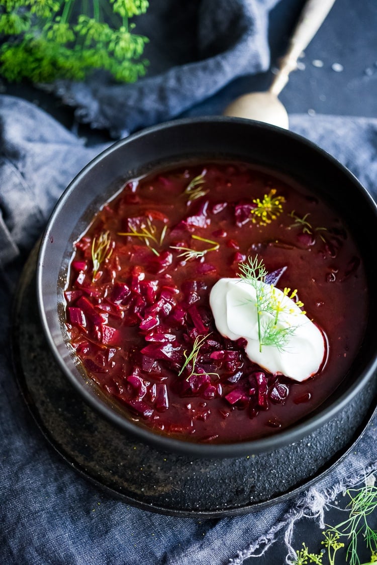 soup bowl with borscht topped with dollop of sour cream and fresh dill.