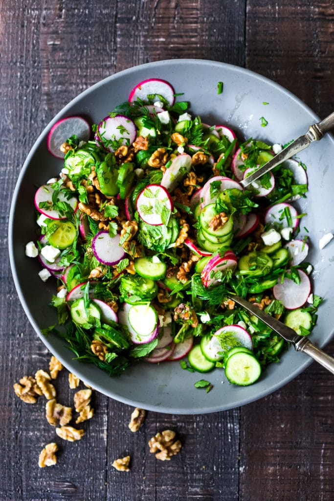 Persian cucumber salad in a grey dish with walnuts and herbs.