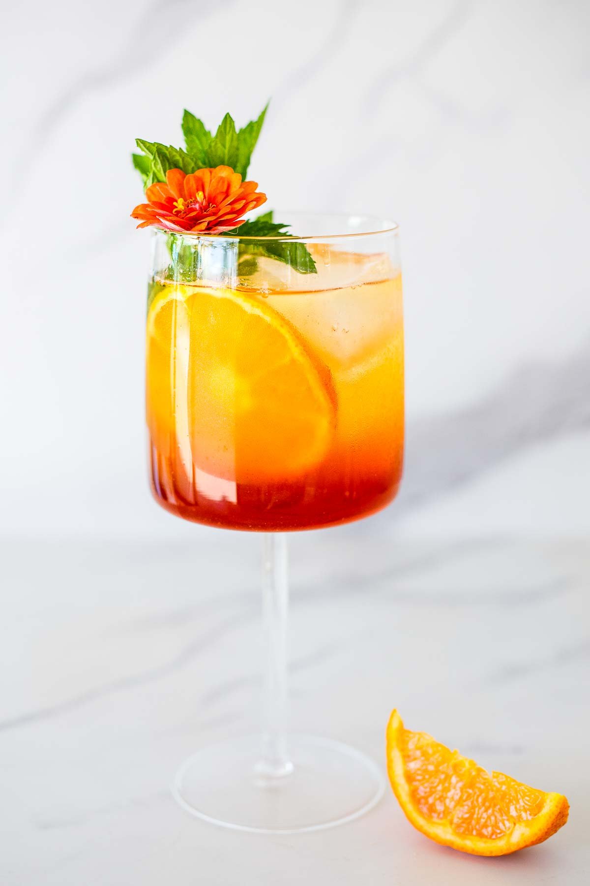 Amaro Spritz in a stemmed glass with mint and orange. 