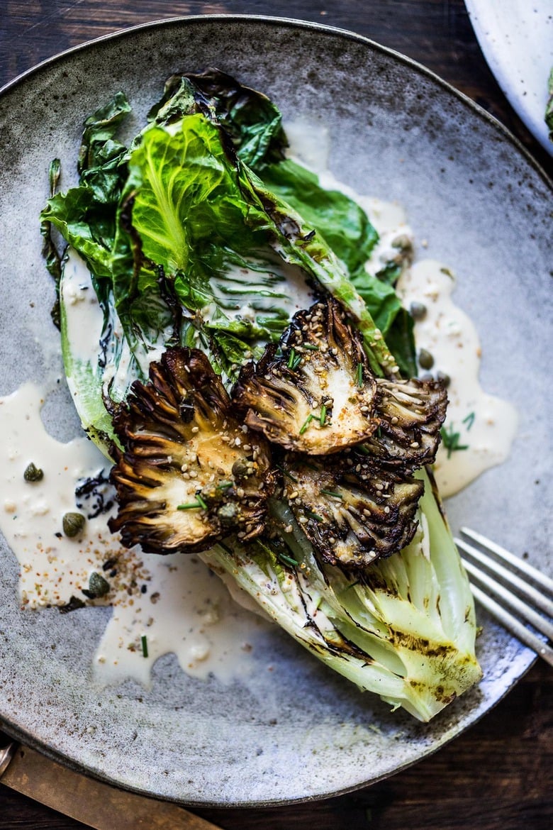 grilled romaine salad with maitake mushrooms and caesar dressing on plate.