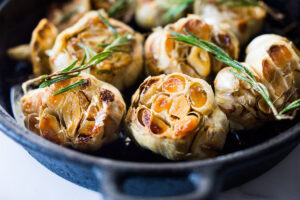 How to Roast Garlic in the oven (using whole heads of garlic or peeled garlic cloves). Roasting garlic transforms it! Spreadable, buttery, sweet, earthy, and complex it has a multitude of uses in the kitchen! And so many health benefits! Whole cloves can be stored in olive oil in the fridge for up to 10 days, or made into a paste, to add to soups, stews, sauces, dressings and mashes. #roastedgarlic #bakedgarlic #garlic #garlicbenefits #roastgarlic