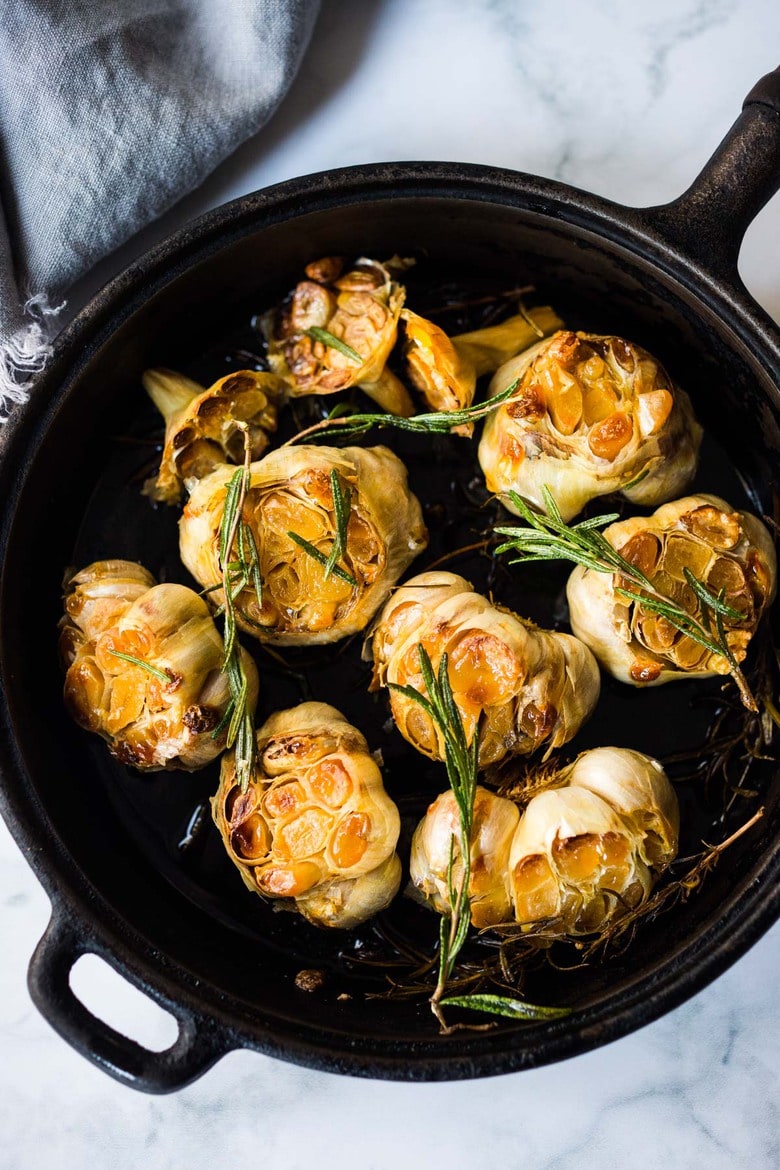 How to Roast Garlic in the oven (using whole heads of garlic or peeled garlic cloves). Roasting garlic transforms it! Spreadable, buttery, sweet, earthy, and complex it has a multitude of uses in the kitchen! And so many health benefits! Whole cloves can be stored in olive oil in the fridge for up to 10 days, or made into a paste, to add to soups, stews, sauces, dressings and mashes. #roastedgarlic #bakedgarlic #garlic #garlicbenefits #roastgarlic